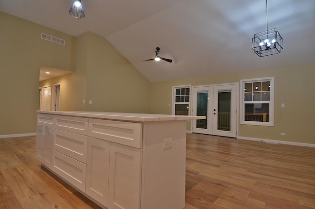 kitchen featuring french doors, lofted ceiling, white cabinetry, hanging light fixtures, and a kitchen island