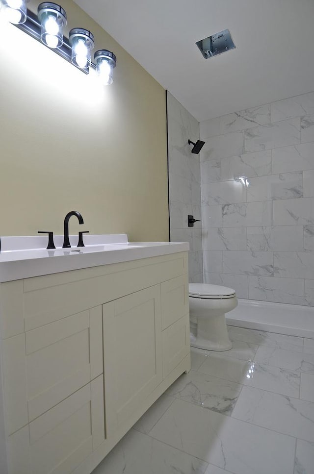 bathroom featuring vanity, tiled shower, and toilet