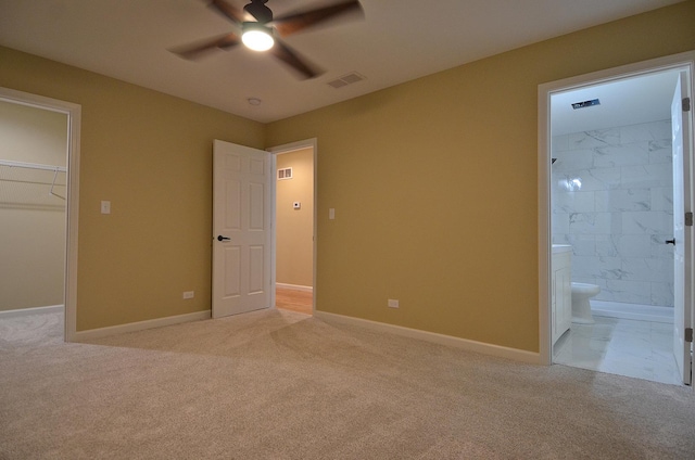 unfurnished bedroom featuring ensuite bathroom, a spacious closet, ceiling fan, light carpet, and a closet