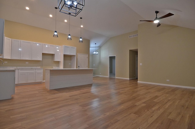 kitchen featuring light hardwood / wood-style flooring, high vaulted ceiling, a center island, and white cabinets