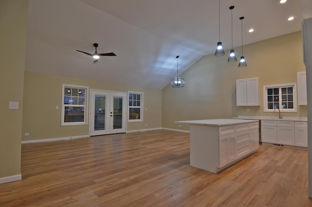 kitchen featuring decorative light fixtures, sink, white cabinets, a center island, and french doors