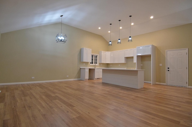 kitchen featuring decorative light fixtures, light wood-type flooring, white cabinets, and a kitchen island