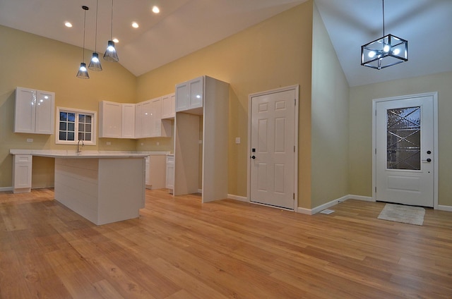 kitchen with sink, a center island, hanging light fixtures, light wood-type flooring, and white cabinets