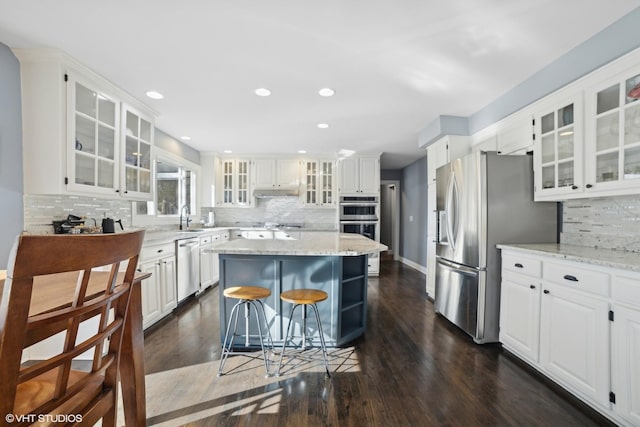 kitchen with a kitchen island, appliances with stainless steel finishes, white cabinetry, sink, and dark wood-type flooring