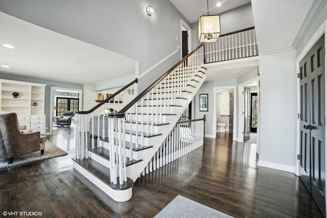 stairs featuring hardwood / wood-style flooring, a high ceiling, and an inviting chandelier