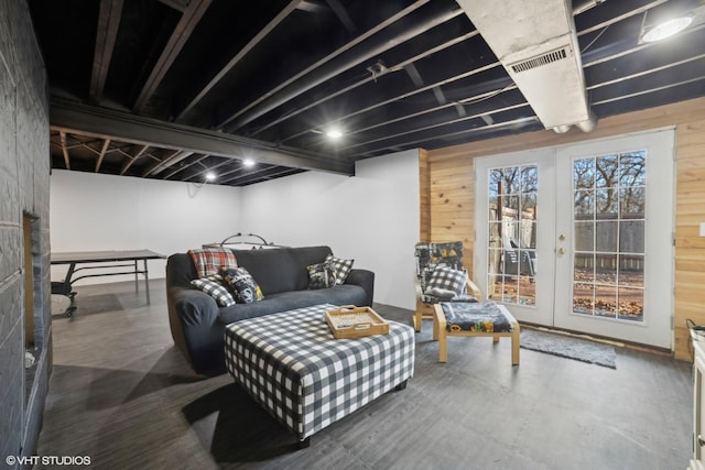 living room featuring french doors and wooden walls