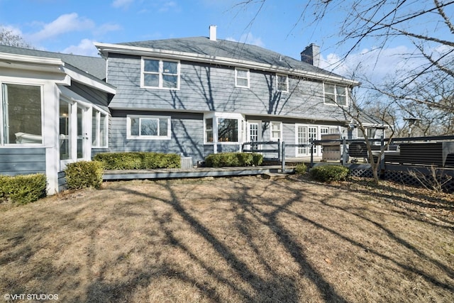 rear view of property featuring a lawn and a deck