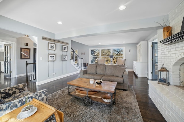 living room featuring a brick fireplace and dark wood-type flooring