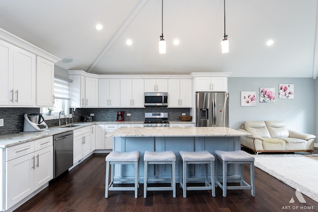 kitchen with a kitchen island, pendant lighting, white cabinetry, lofted ceiling, and stainless steel appliances