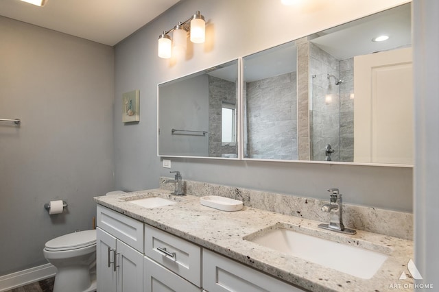 bathroom with vanity, tiled shower, and toilet