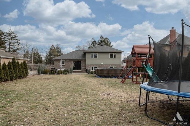 back of property with a pool, a playground, a trampoline, and a lawn