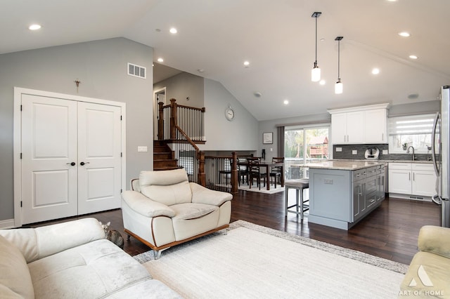 living room featuring high vaulted ceiling, dark hardwood / wood-style floors, and sink