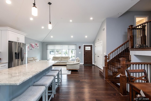 kitchen featuring a breakfast bar area, white cabinetry, stainless steel refrigerator with ice dispenser, dark hardwood / wood-style flooring, and decorative light fixtures