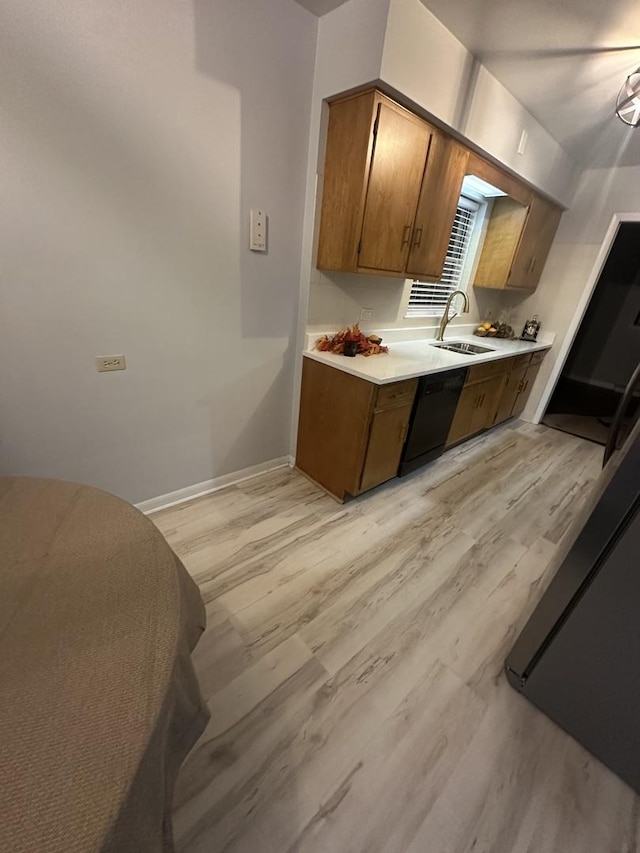 kitchen featuring black dishwasher, sink, and light hardwood / wood-style floors