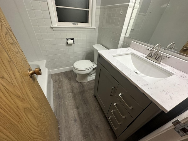 bathroom with vanity, toilet, hardwood / wood-style floors, and tile walls