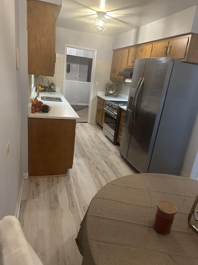 kitchen with tasteful backsplash, stainless steel appliances, sink, and light wood-type flooring