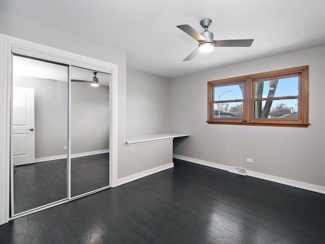 unfurnished bedroom featuring a closet, dark hardwood / wood-style floors, and ceiling fan