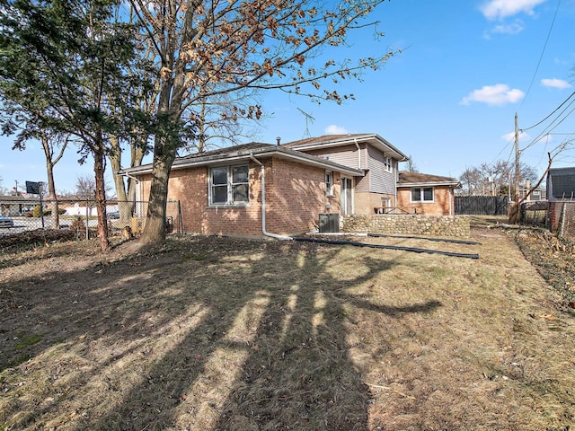 rear view of property featuring central AC and a lawn