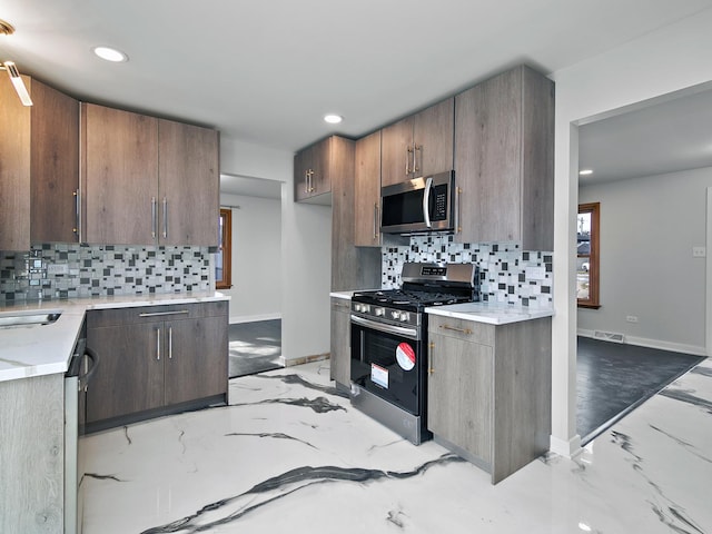 kitchen featuring tasteful backsplash, sink, dark brown cabinetry, and appliances with stainless steel finishes