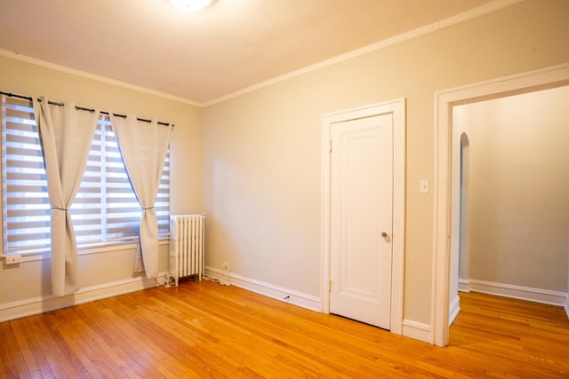 spare room with crown molding, radiator, and light hardwood / wood-style floors