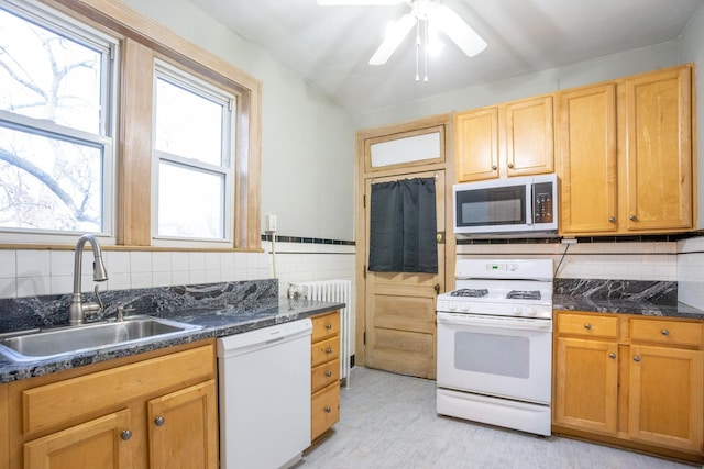 kitchen featuring sink, white appliances, ceiling fan, dark stone countertops, and radiator heating unit