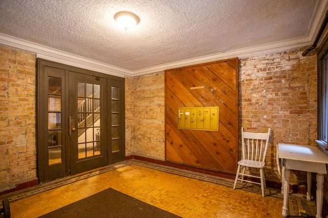 interior space with brick wall, ornamental molding, and a textured ceiling