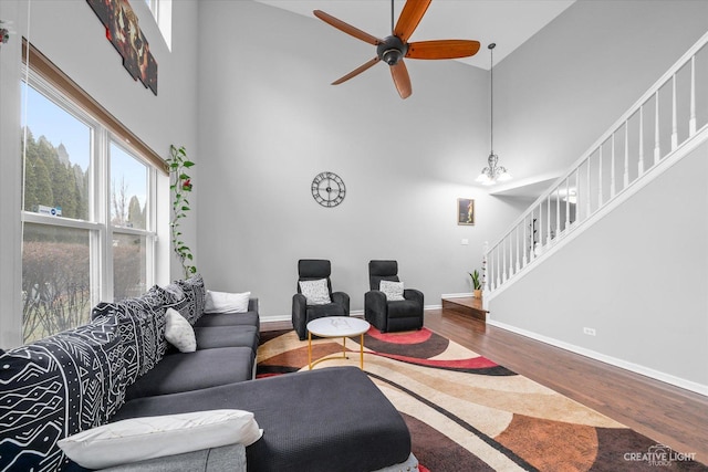 living room with hardwood / wood-style flooring, a towering ceiling, and ceiling fan