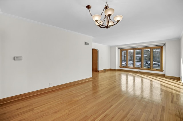 unfurnished living room featuring crown molding, a notable chandelier, and light wood-type flooring