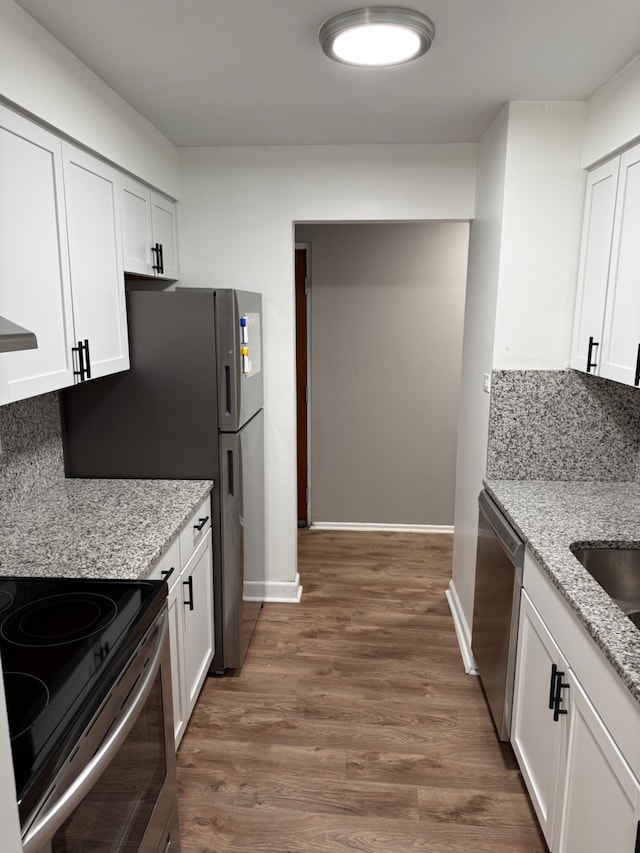 kitchen featuring stainless steel appliances, light stone countertops, decorative backsplash, and white cabinets