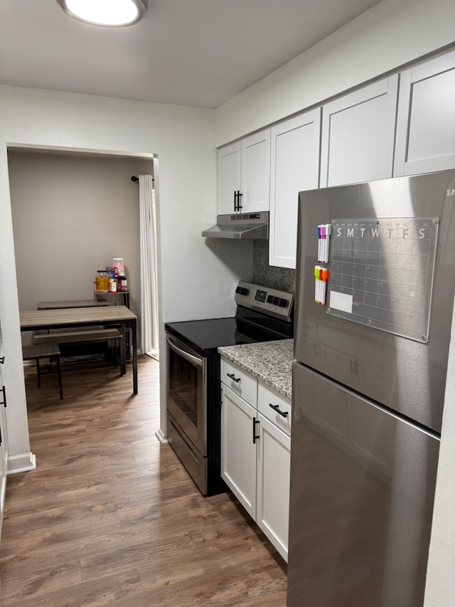 kitchen with appliances with stainless steel finishes, dark hardwood / wood-style flooring, light stone countertops, decorative backsplash, and white cabinets