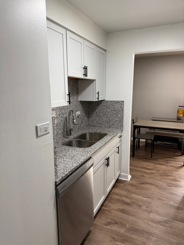 kitchen featuring dishwasher, sink, backsplash, white cabinets, and light stone counters