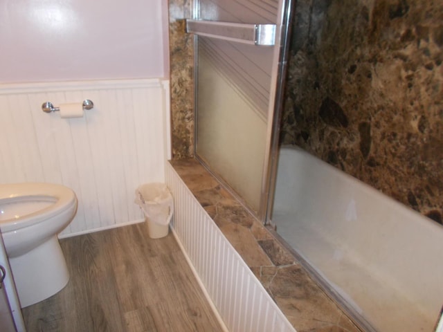 bathroom featuring a shower with shower door, hardwood / wood-style floors, and toilet