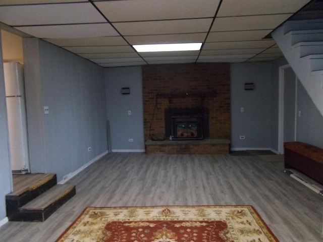 unfurnished living room with a brick fireplace, hardwood / wood-style floors, and a drop ceiling