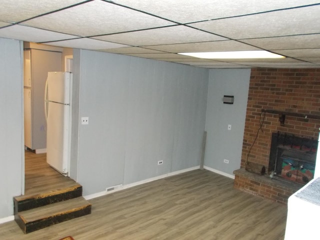 living room with a drop ceiling, a fireplace, and wood-type flooring