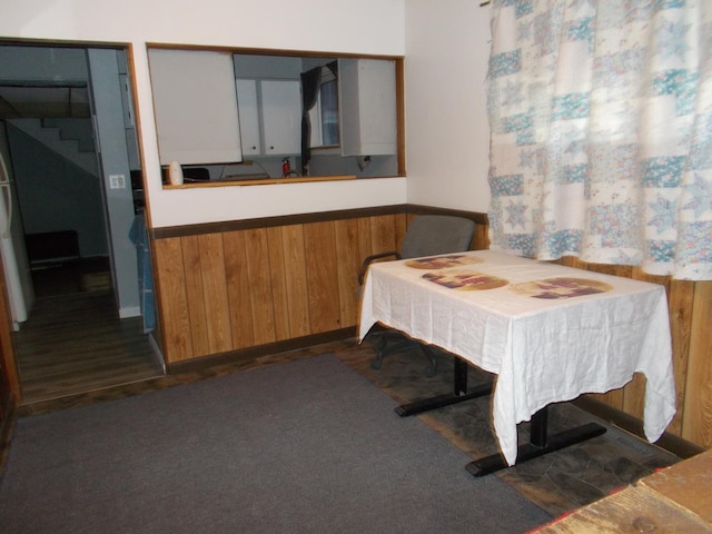 dining space featuring dark wood-type flooring and wooden walls