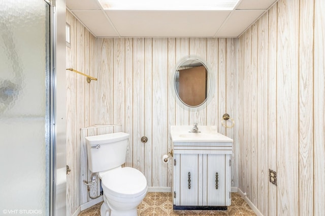 bathroom featuring vanity, wooden walls, and toilet