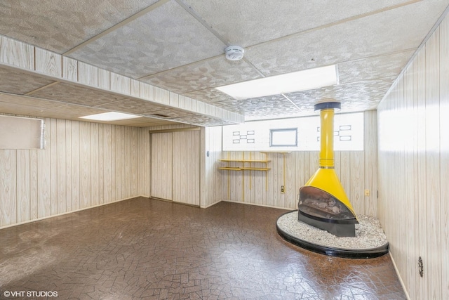 basement featuring wood walls and a wood stove