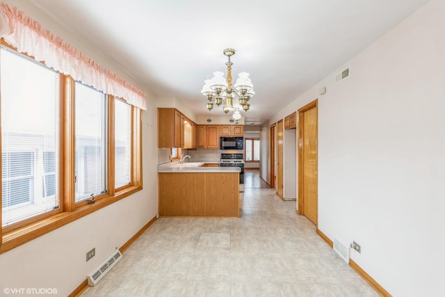 kitchen featuring sink, a chandelier, hanging light fixtures, stainless steel range with gas stovetop, and kitchen peninsula