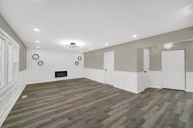 unfurnished living room featuring dark wood-type flooring and an inviting chandelier