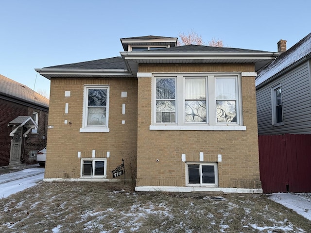 snow covered property featuring fence and brick siding