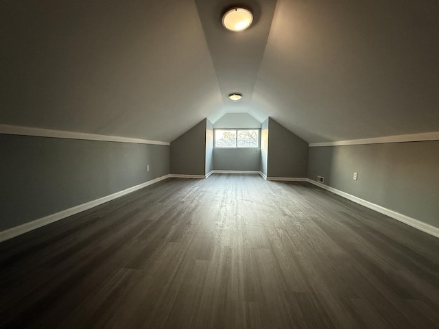 additional living space featuring dark wood-type flooring and lofted ceiling