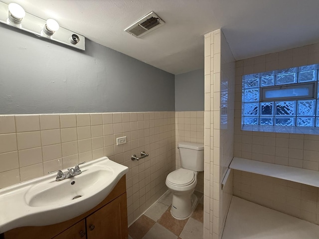 bathroom with vanity, toilet, and tile walls