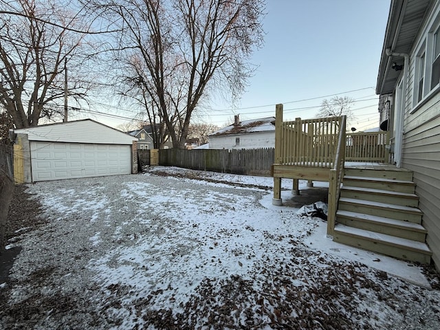 snowy yard with a garage and an outbuilding