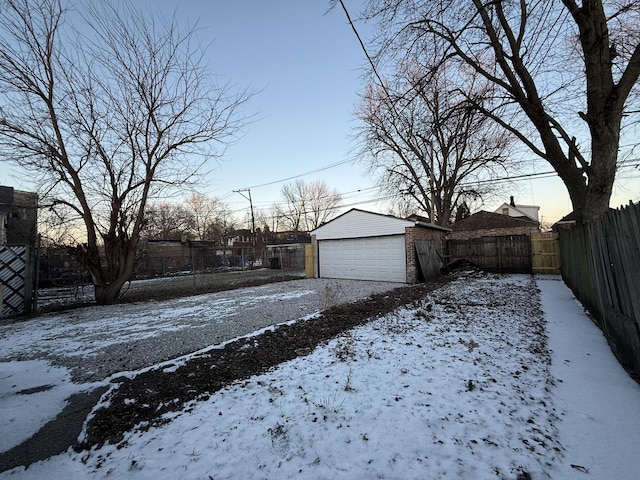 yard layered in snow with an outbuilding and a garage