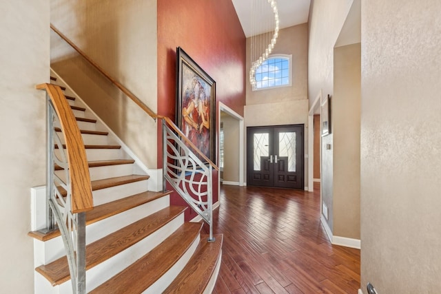 foyer featuring french doors, dark wood-type flooring, a high ceiling, and a healthy amount of sunlight