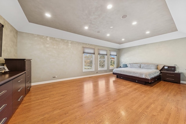 bedroom featuring light wood-type flooring and a raised ceiling