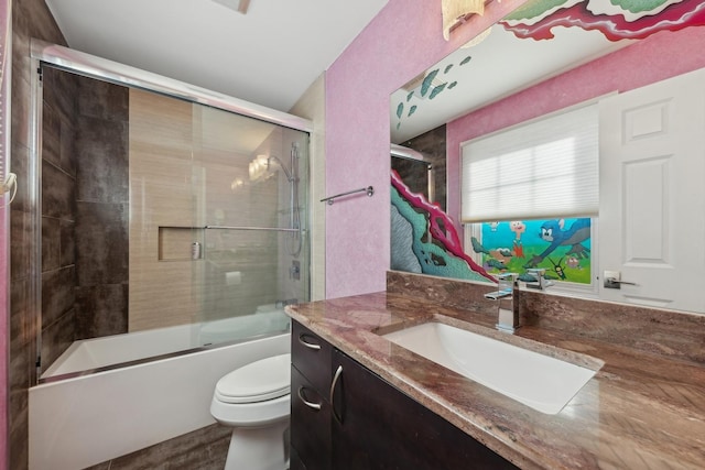 full bathroom featuring vanity, combined bath / shower with glass door, and toilet