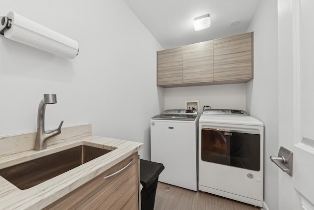 washroom featuring light hardwood / wood-style floors, cabinets, sink, and separate washer and dryer