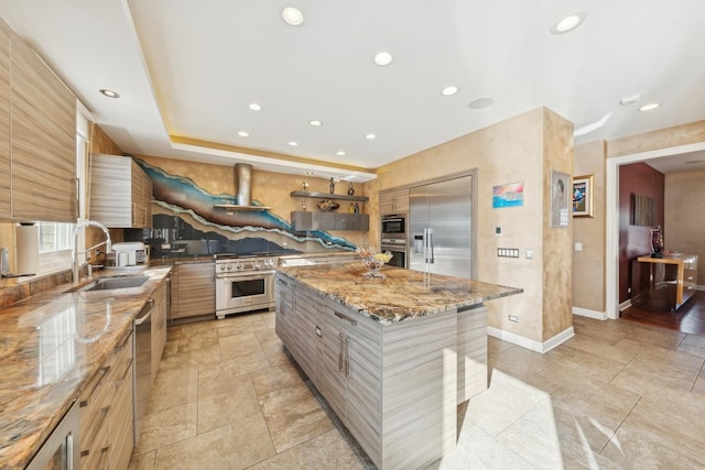 kitchen with sink, premium appliances, a center island, and light stone counters