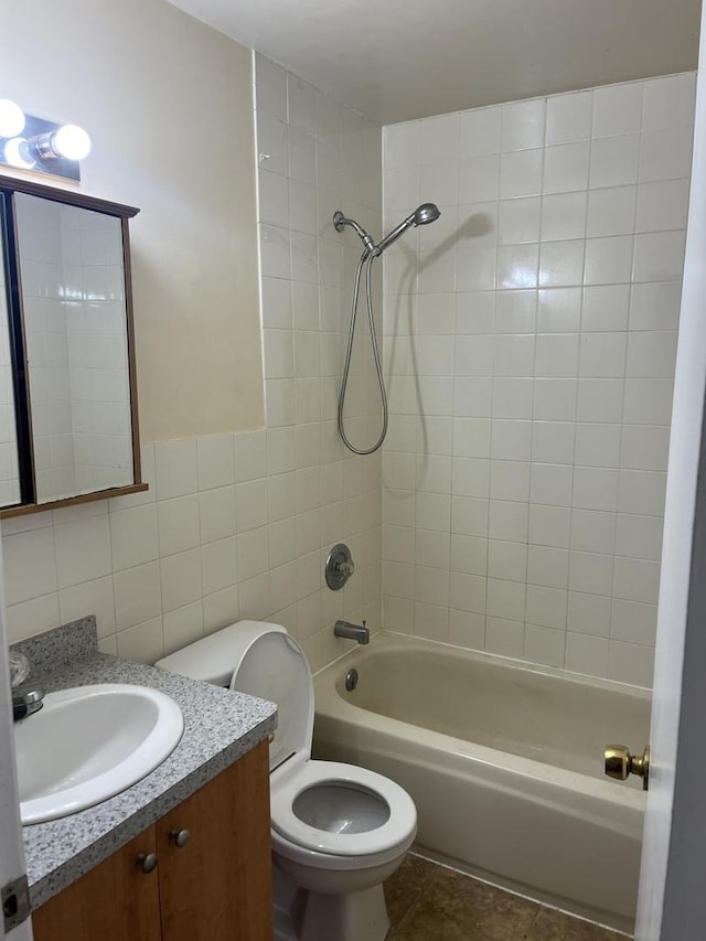 full bathroom with tile patterned flooring, tile walls, vanity, toilet, and tiled shower / bath